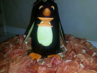 Party platter with a penguin shitting on a pile of Prosciutto.